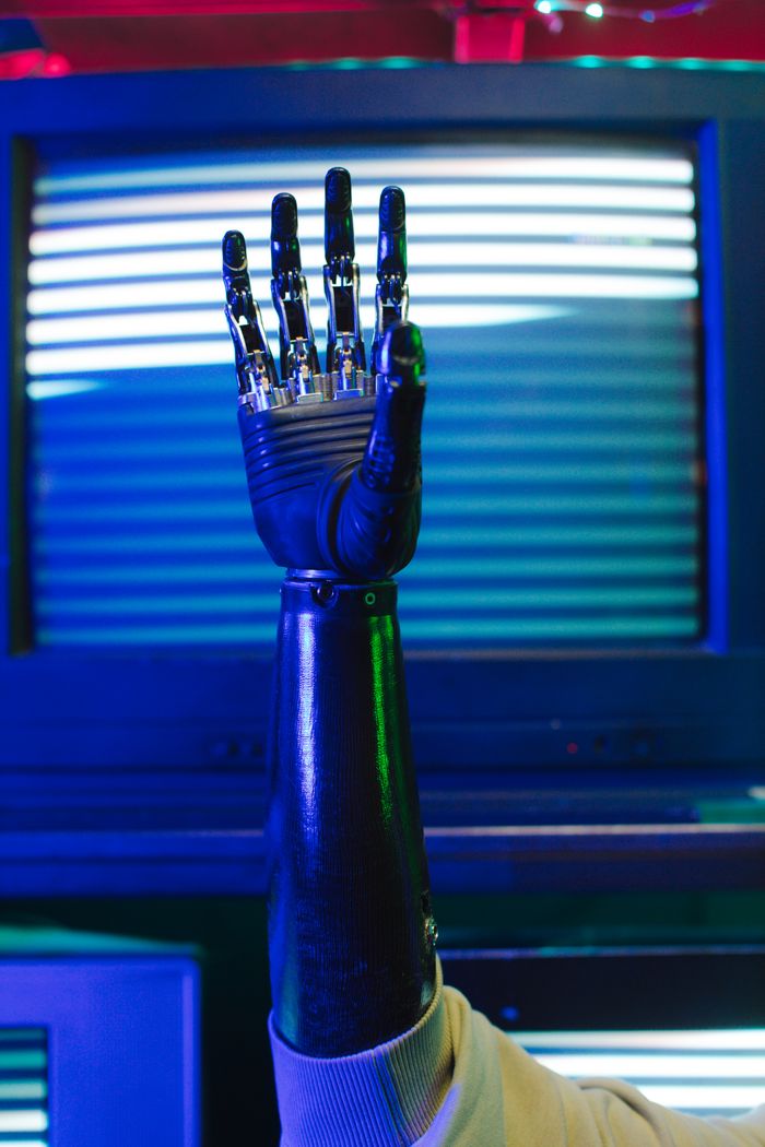 services-06 Close-up of a bionic prosthetic arm raised against retro tech background.